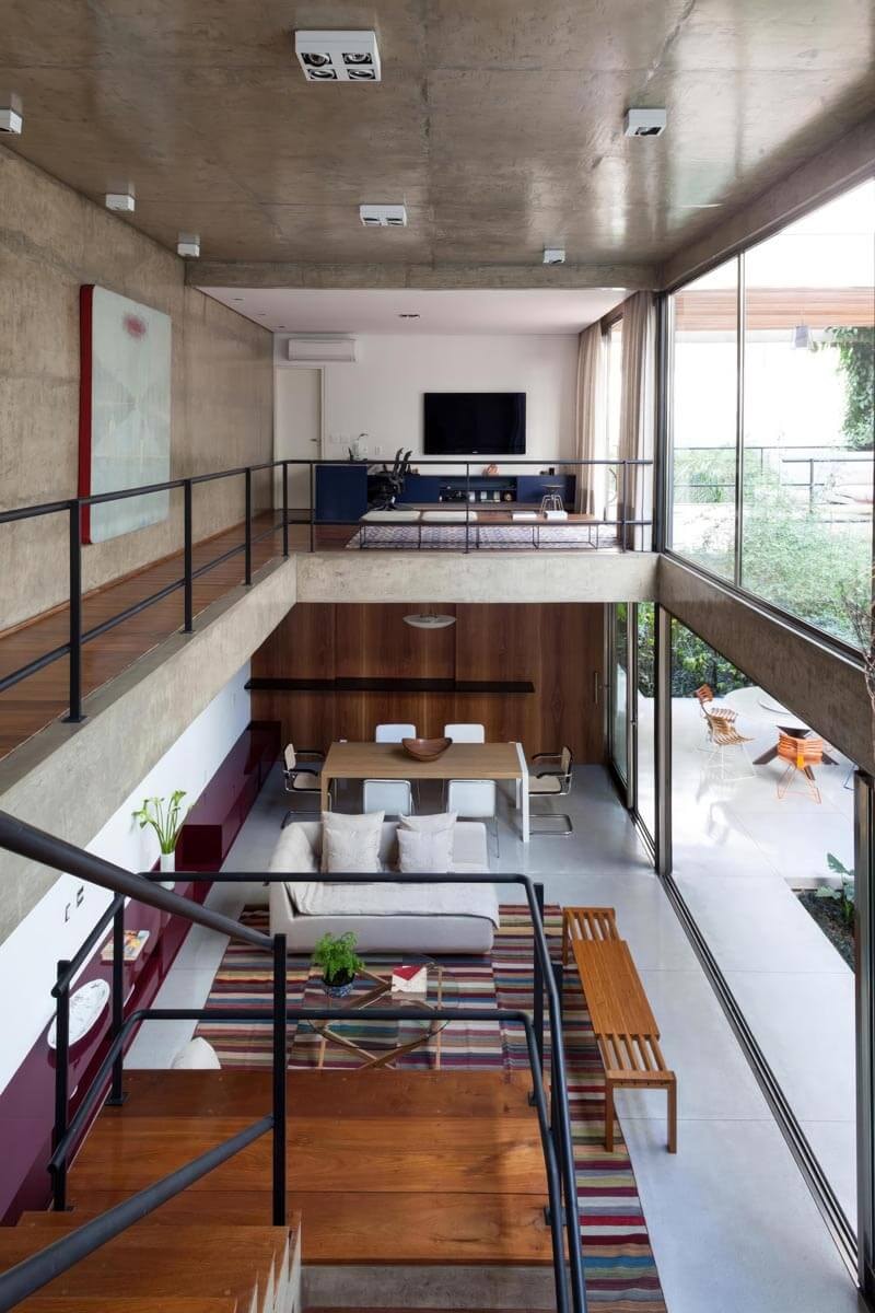 Gallery floor of a modern loft in industrial architecture with a concrete ceiling and walkway beside the staircase leading down.